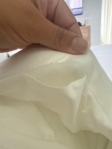 Hand lifting a corner of the cool-touch comforter fabric